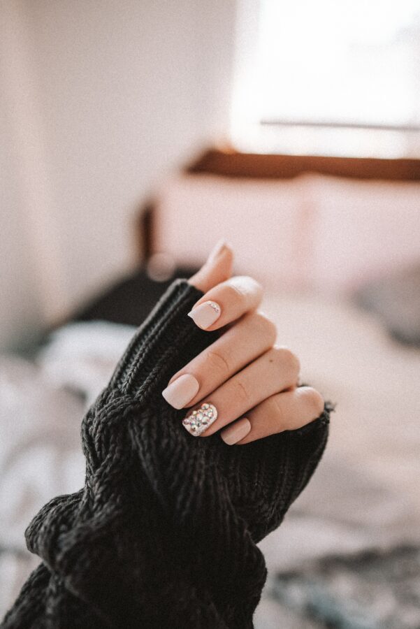 hand holding sweater cuff acrylic nails at home. 