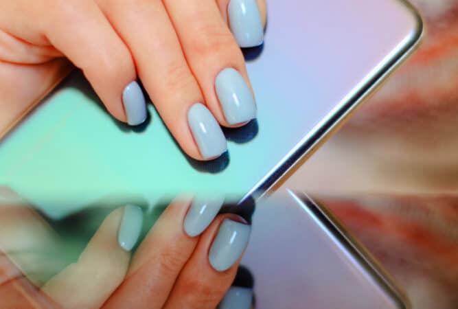 teal blue acrylic nails hands holding phone.