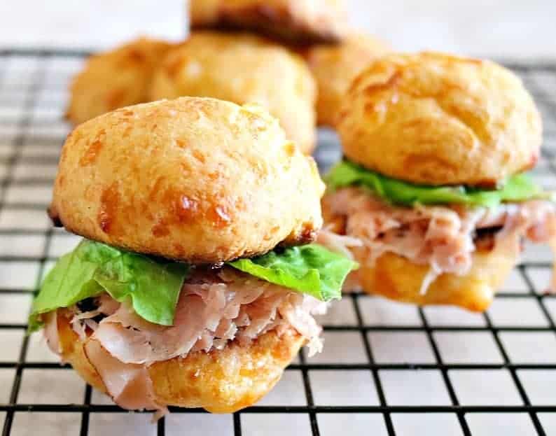 ham slider roll sandwiches with lettuce on a wire rack. 