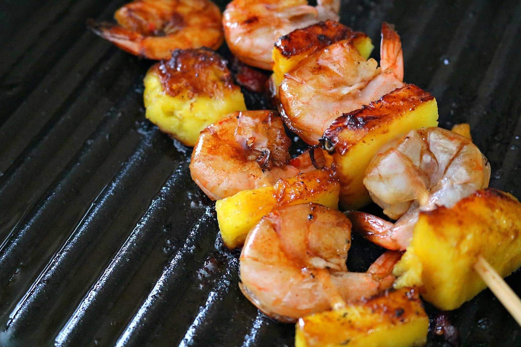 pineapple and shrimp skewers on grill. 