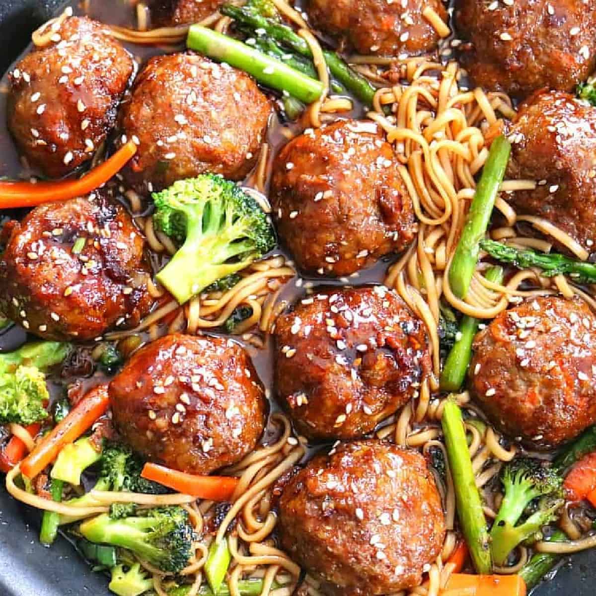 sesame chicken meatballs with lo mein in skillet.