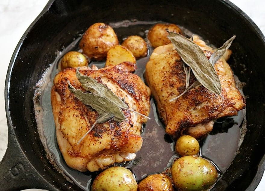 chicken thighs with potatoes in a cast iron skillet. 