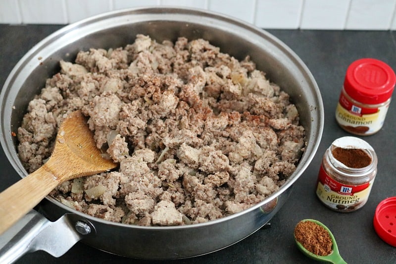 Ground pork crumbles cooked and being seasoned in skillet