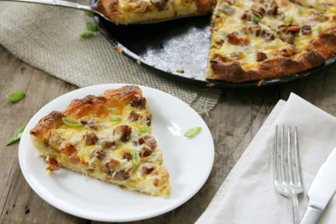 a meat lover's fathead pizza slice on a plate next to a skillet. 