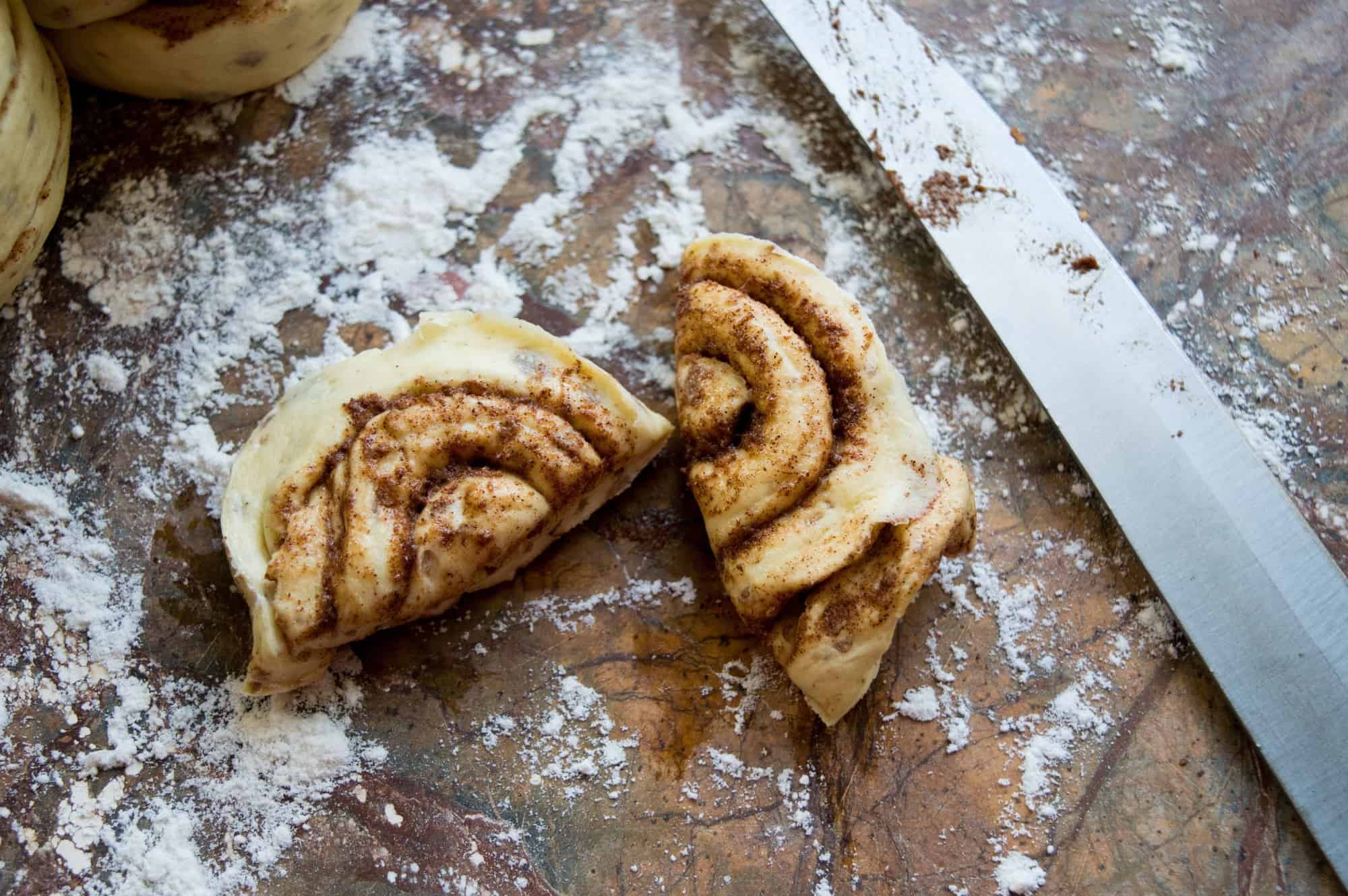 Cinnamon roll cut in half on cutting board