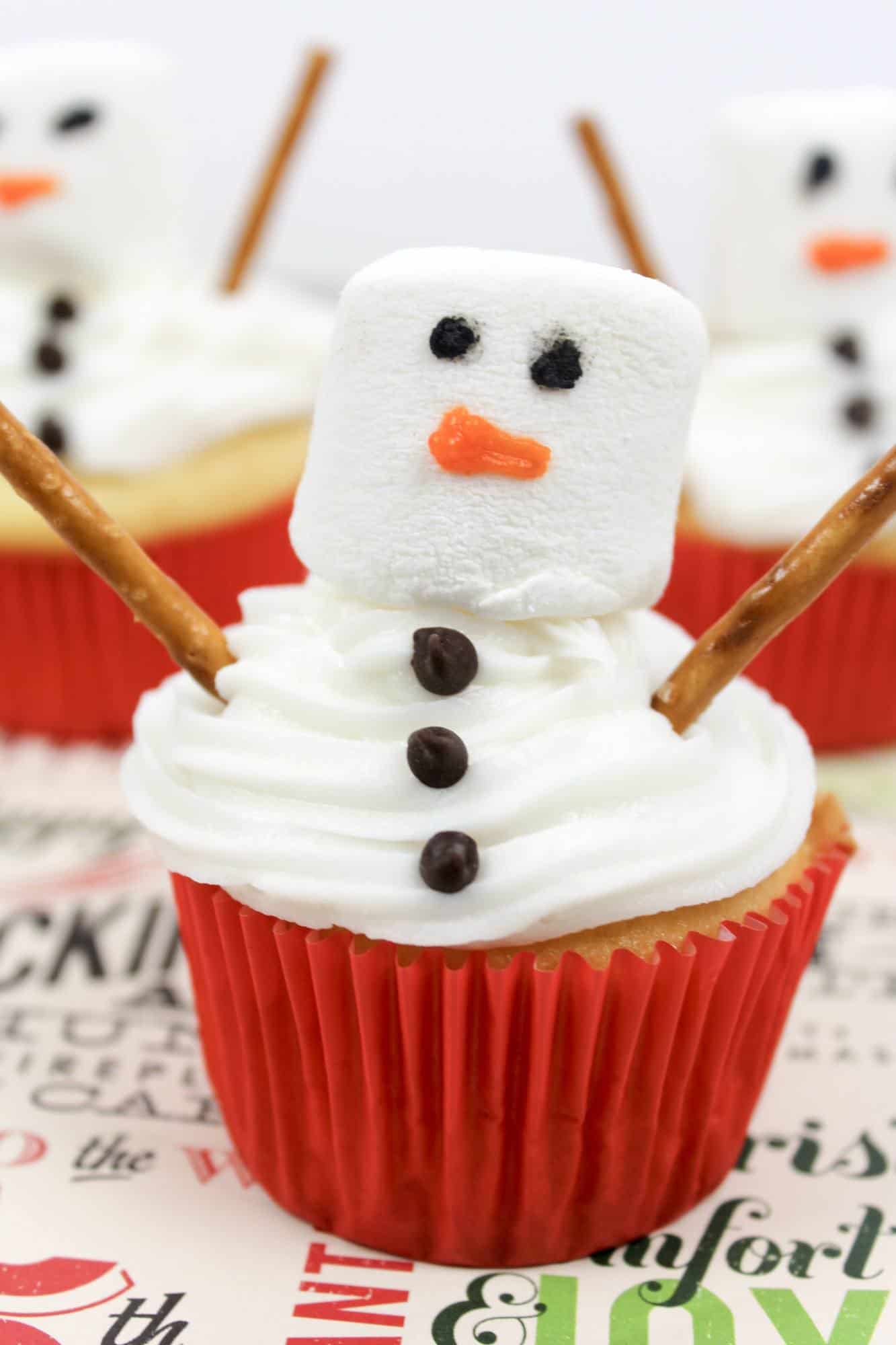 a vanilla cupcake with vanilla frosting as a snowman.