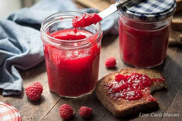 sugar free strawberry jam in a mason jar on wood cutting board. 