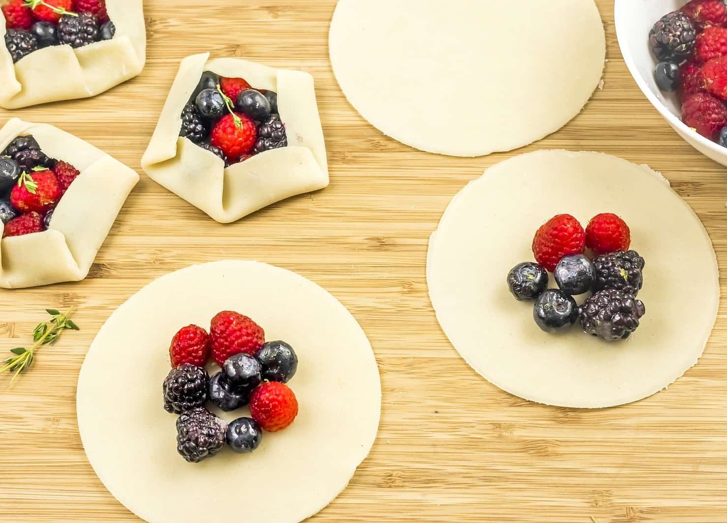 dough cut into circle with fruit on cutting board.