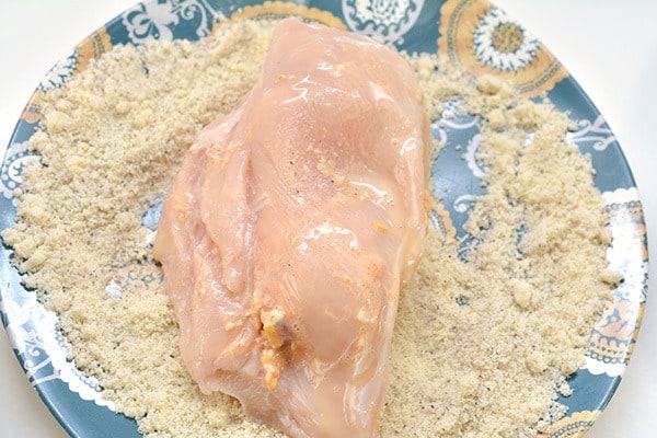 chicken breast being coated with seasoning