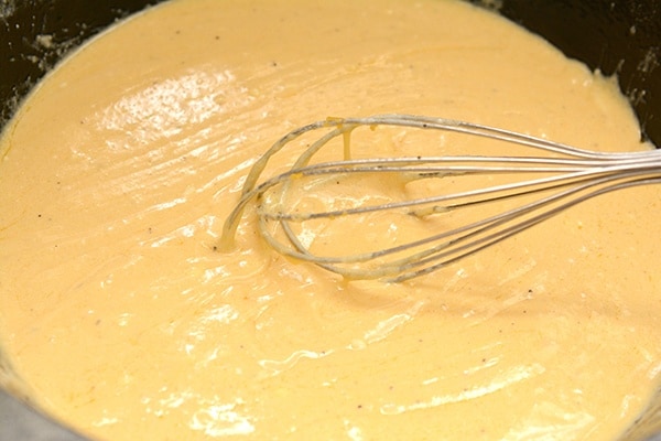 a prepared cheese sauce in a pot with whisk. 