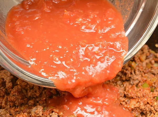 tomatoes pouring into chili mixture