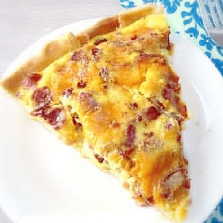 slice of bacon cheese quiche on plate.