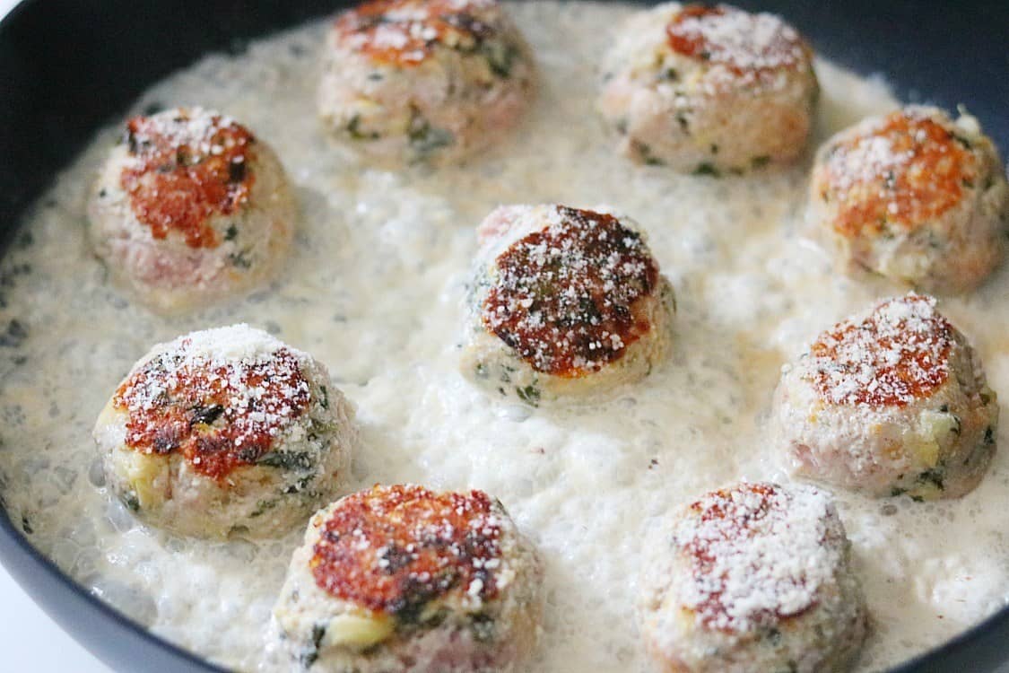 parmesan cream sauce in skillet with meatball. 