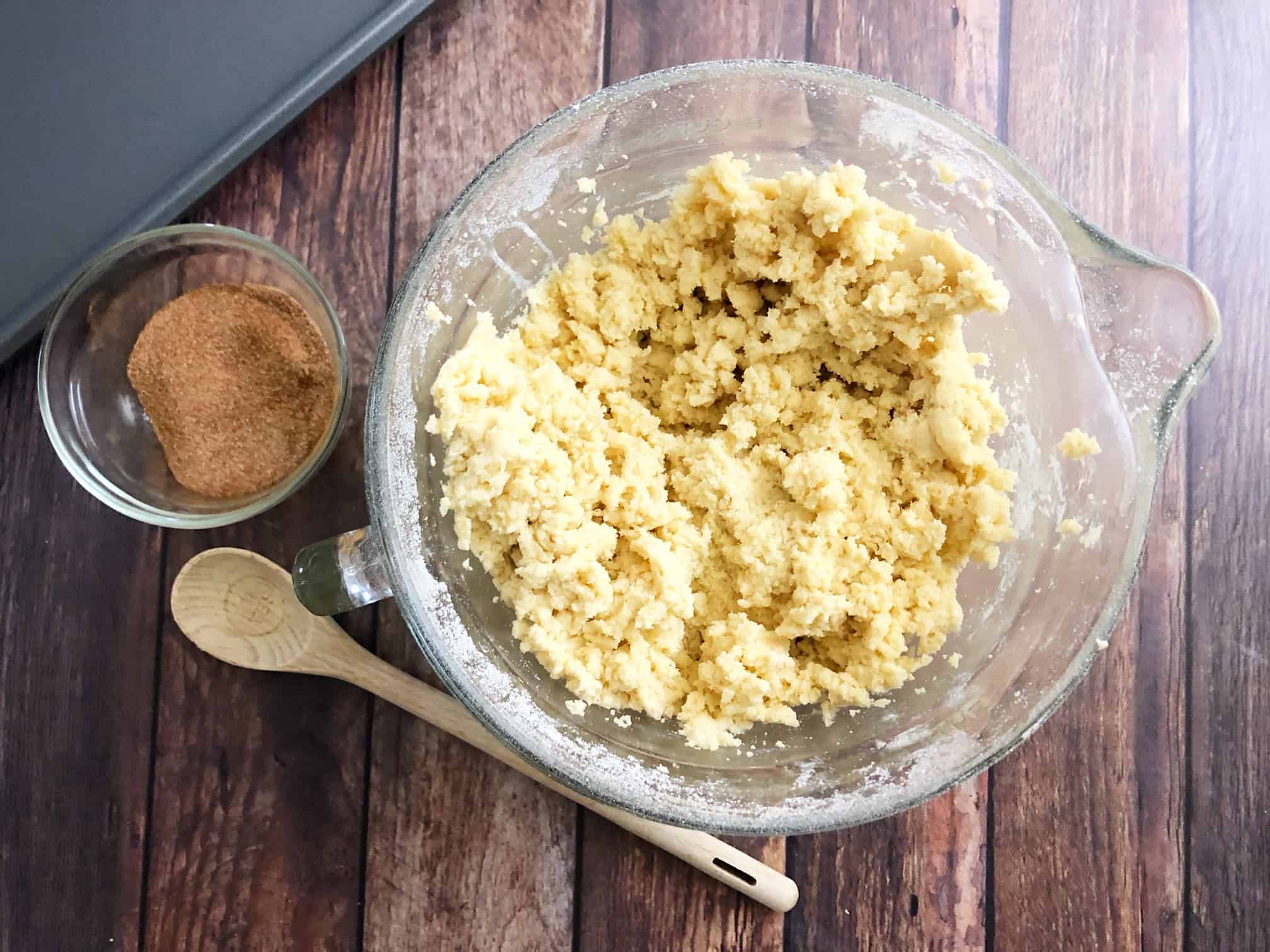 a bowl of cinnamon next to cookie dough. 