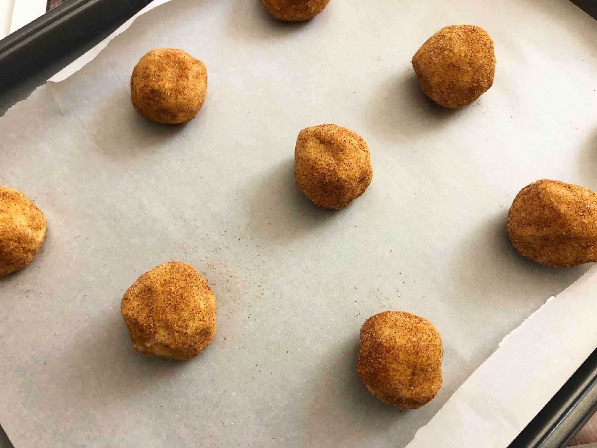 cookie dough rolled into balls on a cookie baking sheet. 