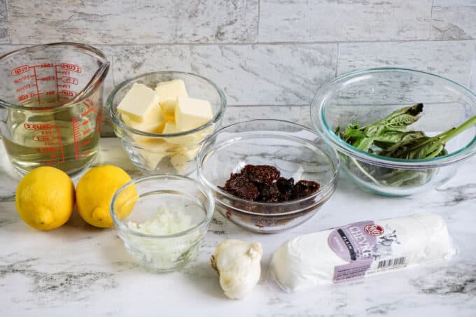 ingredients like lemon, butter and cheese in prep bowls on the counter.