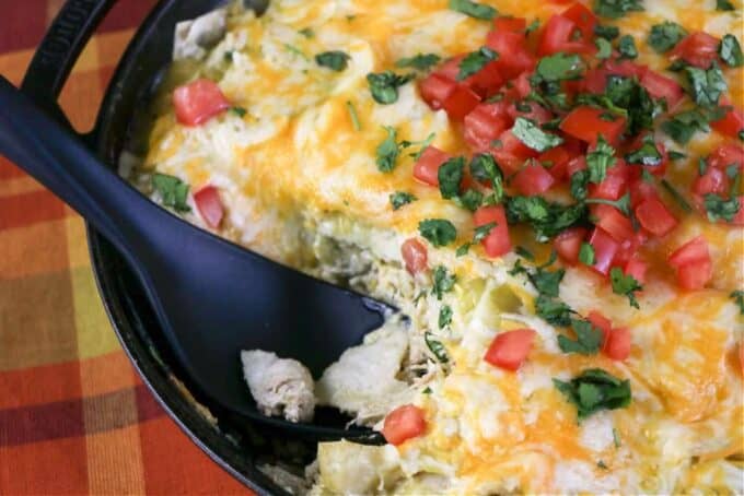 spoon scooping enchiladas from a skillet.