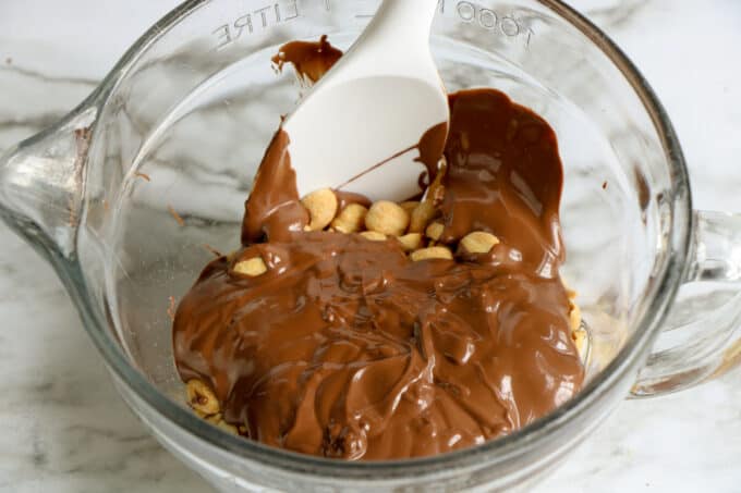 melted chocolate being stirred with peanuts. 