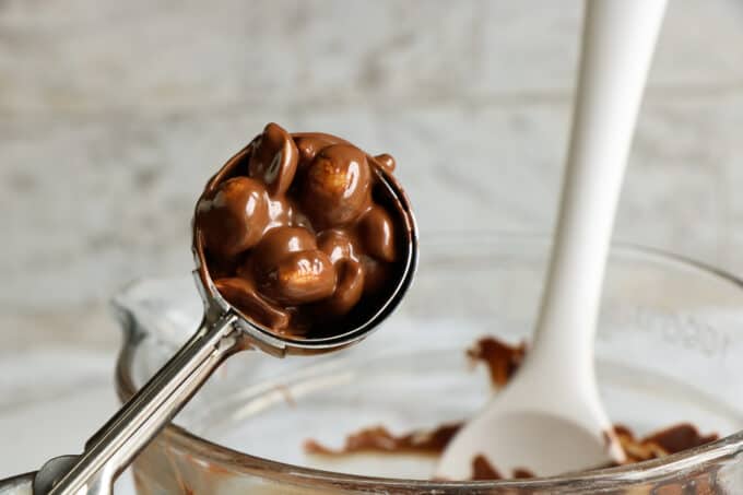 a scoop of melted chocolate with peanuts in it. 