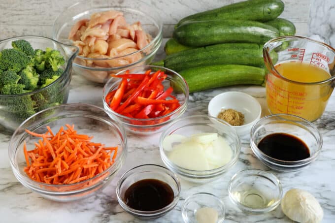 ingredients for keto chinese food including zucchini, diced chicken and veggies in prep bowls. 