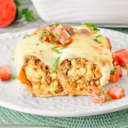 breakfast enchilada cut in half showing egg and sausage with tomato.