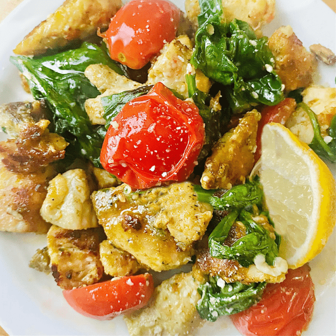 keto garlic chicken with a lemon wedge and cherry tomatoes. 