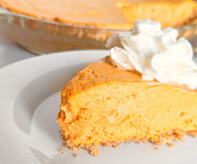 thick slice of low carb no bake pumpkin cheesecake on white plate. 