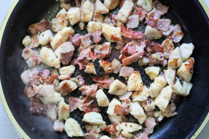 chicken breast and bacon in skillet.