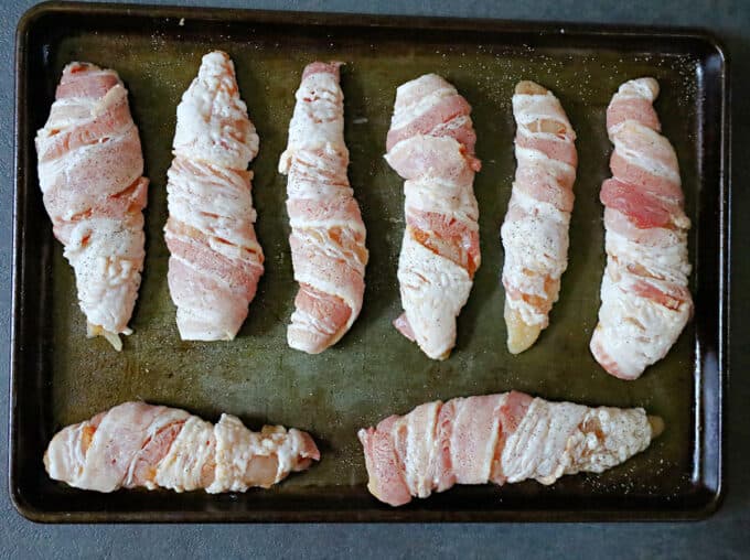 chicken wrapped in bacon on sheet pan. 