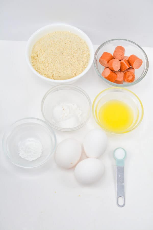 ingredients for corn dogs hot dogs, almond flour, eggs, oil, sugar, salt in individual bowls.