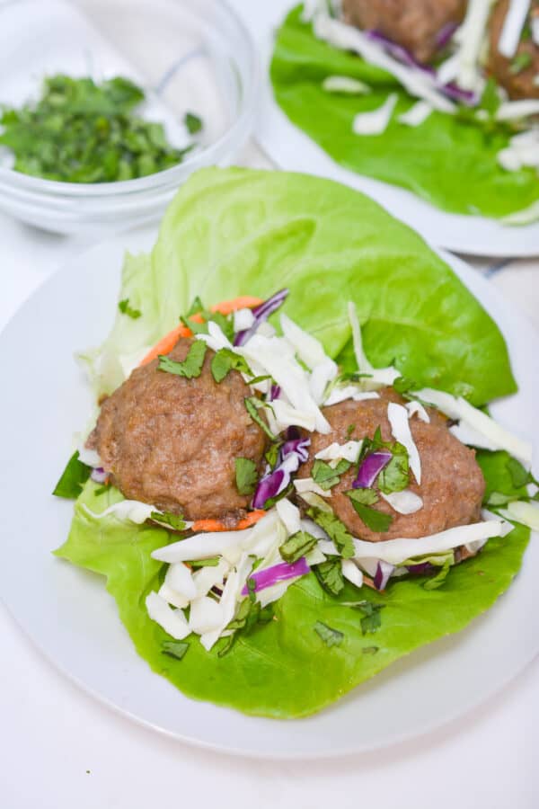 Keto Thai meatballs on lettuce on table.