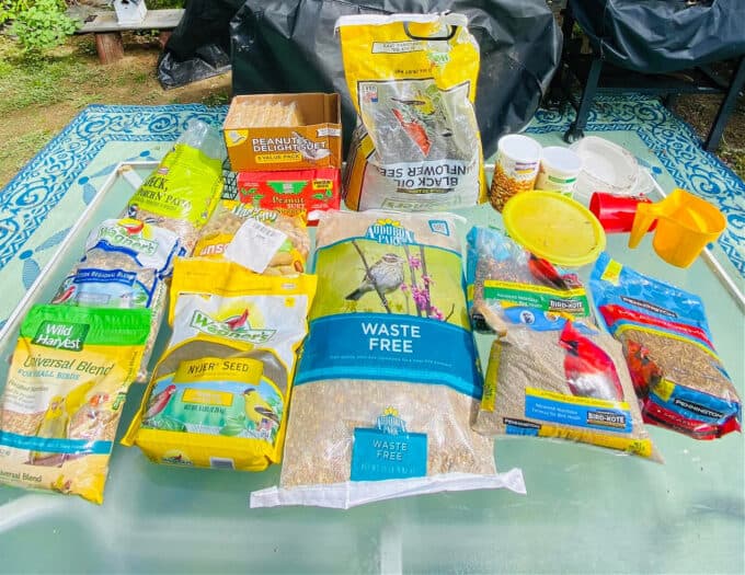 bags of different bird food types on table. 