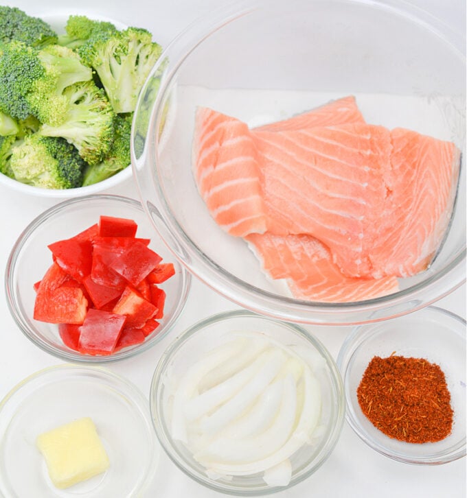 ingredients for salmon foil packets in dishes on white table.