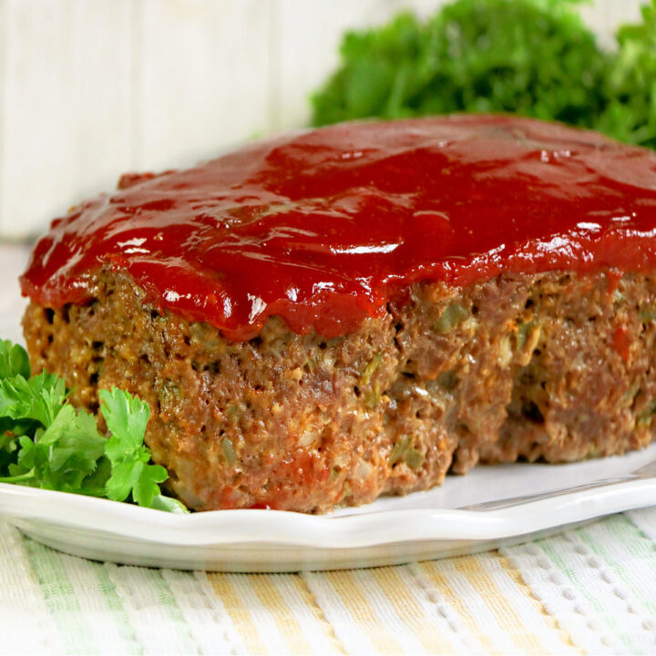a rectangle piece of meatloaf on a white plate.