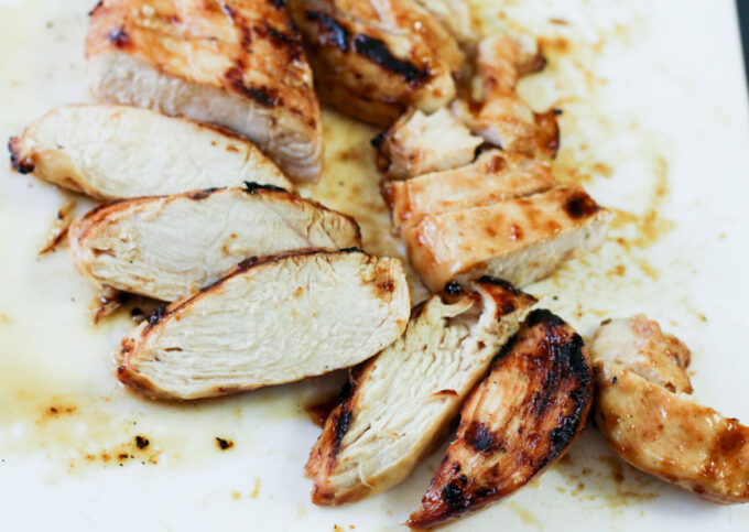 sliced grilled chicken on a white plate. 