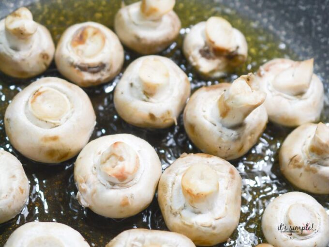 Mushrooms sautéing in a skillet with olive oil