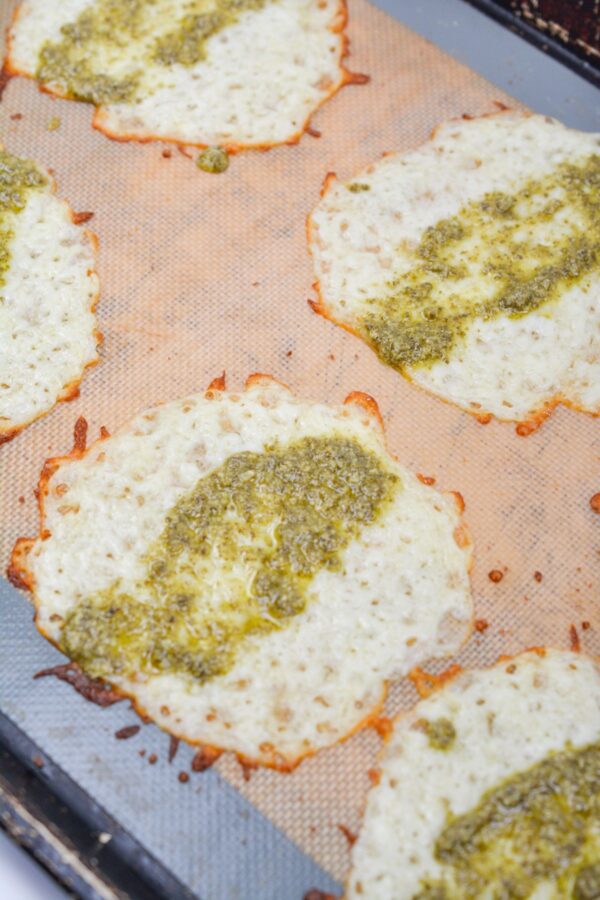 Pesto, layered ont​o baked mozzarella c⁠ircles before r‌ollin‍g.​
