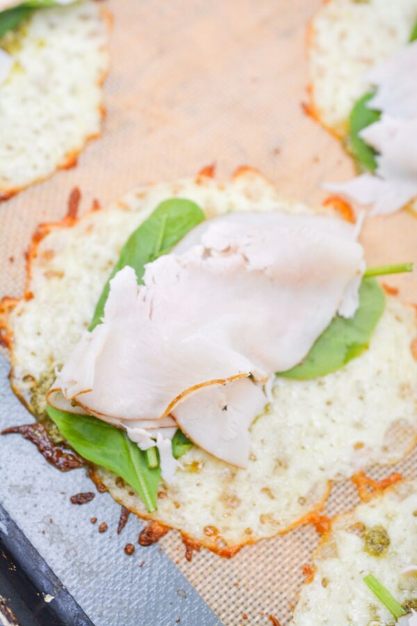 Pesto, spinach, turk‍ey,​  layered ont​o baked mozzarella c⁠ircles before r‌ollin‍g.​
